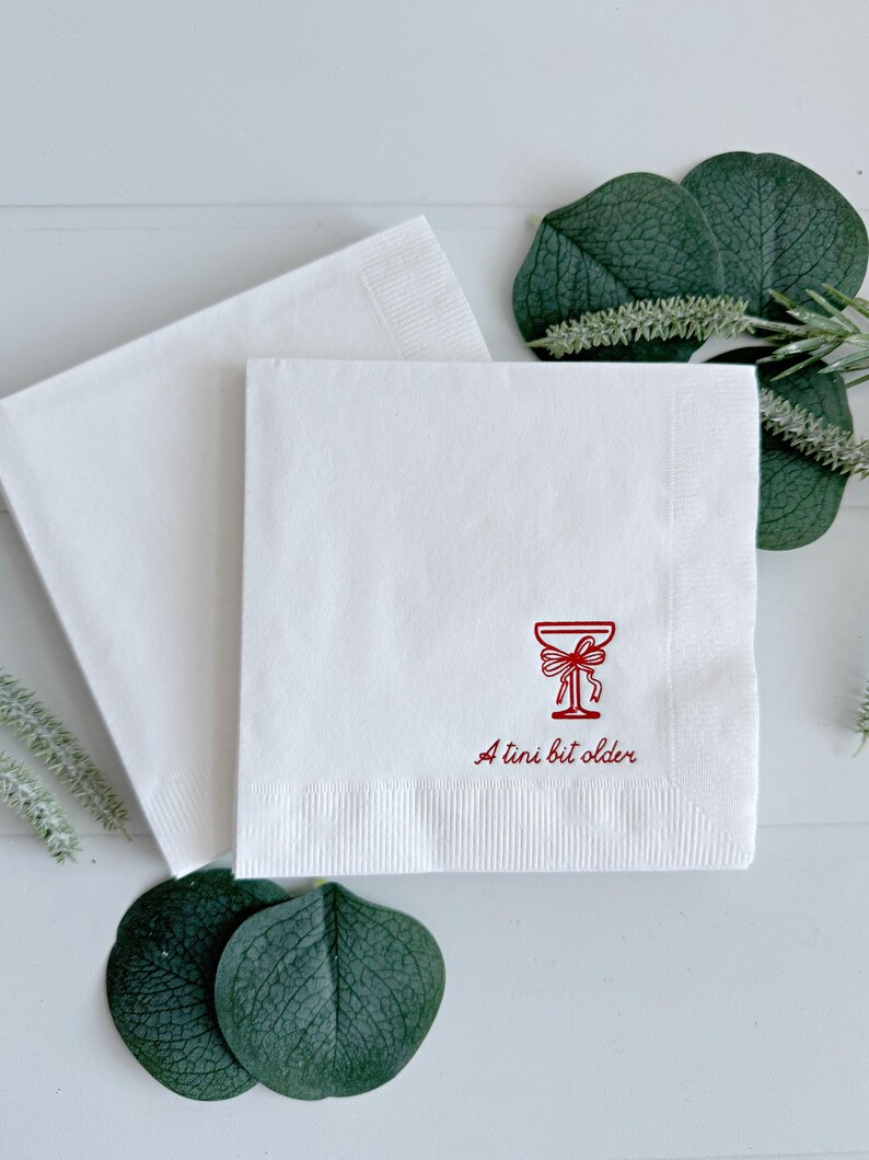 Celebrate a milestone in style with these charming A Tini Bit Older Martini Cocktail Napkins, the perfect addition to any martini-themed birthday party or sophisticated gathering. Designed for lovers of elegant cocktails, these foil-stamped napkins feature a chic illustration of a classic coup martini glass wrapped with a delicate bow around the stem, adding a playful yet refined touch to your celebration. These are perfect for any age birthday, give them as gift for the martini lover.