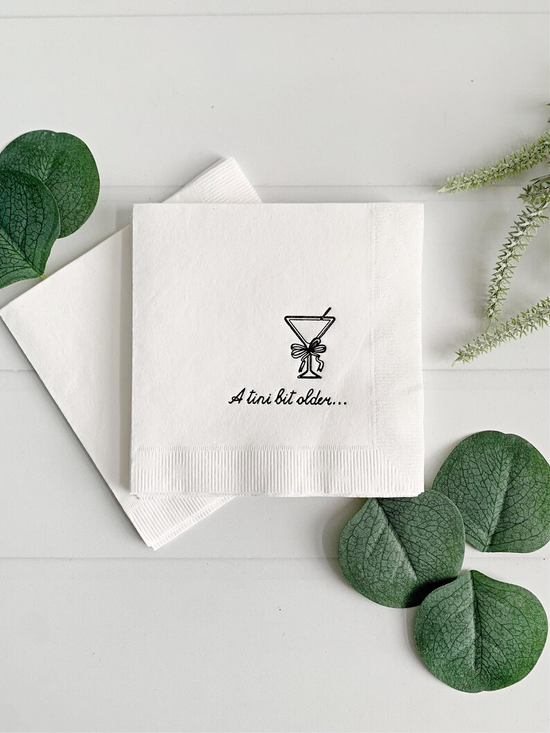 Celebrate a milestone in style with these charming A Tini Bit Older Martini Cocktail Napkins, the perfect addition to any martini-themed birthday party or sophisticated gathering. Designed for lovers of elegant cocktails, these foil-stamped napkins feature a chic illustration of a classic coup martini glass wrapped with a delicate bow around the stem, adding a playful yet refined touch to your celebration. These are perfect for any age birthday, give them as gift for the martini lover.