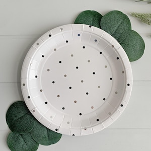 May include: White paper party plate with a black and silver polka dot pattern.