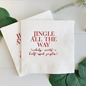 May include: White paper napkins with red text that reads "Jingle All The Way (nobody wants a half-assed jingler)".