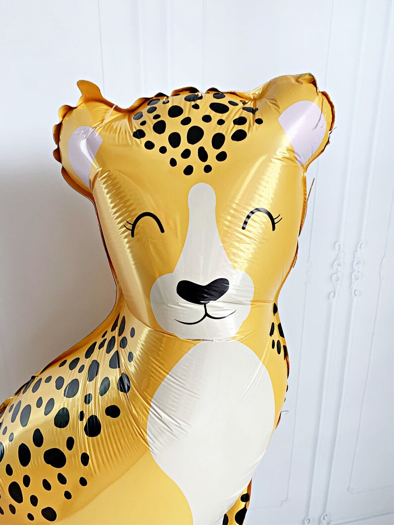 K&ouml;nnte beinhalten: Ein gro&szlig;er, goldfarbener Ballon in Form eines Geparden mit schwarzen Flecken und wei&szlig;en Akzenten. Der Ballon hat ein l&auml;chelndes Gesicht mit geschlossenen Augen. Ideal f&uuml;r eine Geburtstagsfeier oder eine festliche Veranstaltung.