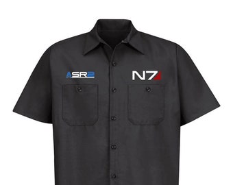 May include: A black short-sleeved work shirt with a white button-up front. The shirt has two chest pockets with buttons and features the text "N7" in red and "ASR2" in blue.