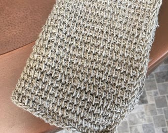 May include: A close-up of a beige, woven, textured bath scrub. The scrub is made of natural fibers and has a rough texture.