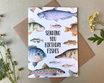 May include: A greeting card with watercolor illustrations of various fish species, including a catfish, perch, and trout. The card reads "Sending You Birthday Fishes" in black text. The card is on a neutral background with a brown envelope and floral accents.