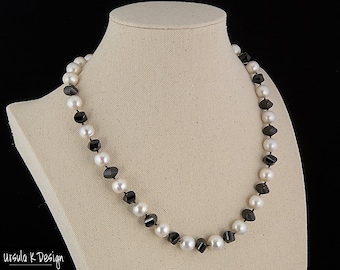 Puede incluir: Un collar de perlas blancas y negras con cuentas facetadas negras. El collar se muestra en un maniquí blanco.