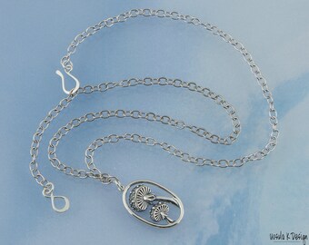 May include: A silver chain necklace with a pendant featuring a detailed design of two mushrooms. The pendant is oval-shaped and has a smooth, polished finish.