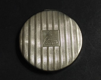 Small round silver tone Tre-Jur compact, textured stripes on top, girl in hoop skirt logo on front, 1923-1924.