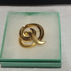 Signed Tona brooch pin, shiny gold tone and brushed gold tone, 1980s, wraparound swirl with a tail.