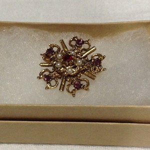 Tiny vintage brooch, gold tone, 5 faux pearls surrounding center red rhinestone, 6 dark pink rhinestones form an outer ring on brooch.