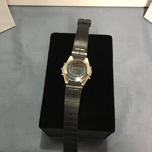 May include: A silver and black wristwatch with a black rubber strap. The watch is on a black velvet display stand.