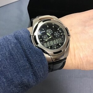 May include: A silver and black digital wristwatch with a black face and a silver band. The watch has a black digital display that reads "11:13:36" and the words "WR 100FT" and "SONIC" are visible on the face.
