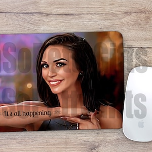 May include: A purple and brown mouse pad with a woman's portrait and the text "It's all happening" in black.
