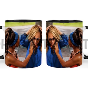 May include: A ceramic mug featuring a black handle and rim, decorated with a photographic print of a person in a blue shirt and sunglasses touching their hair, mirrored on both sides, with the letters OH and TS visible on the mug surface.