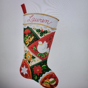 May include: A red, green, and white Christmas stocking with a patchwork design. The stocking is personalized with the name "Lauren" and features a white dove, snowflakes, and poinsettia flowers.