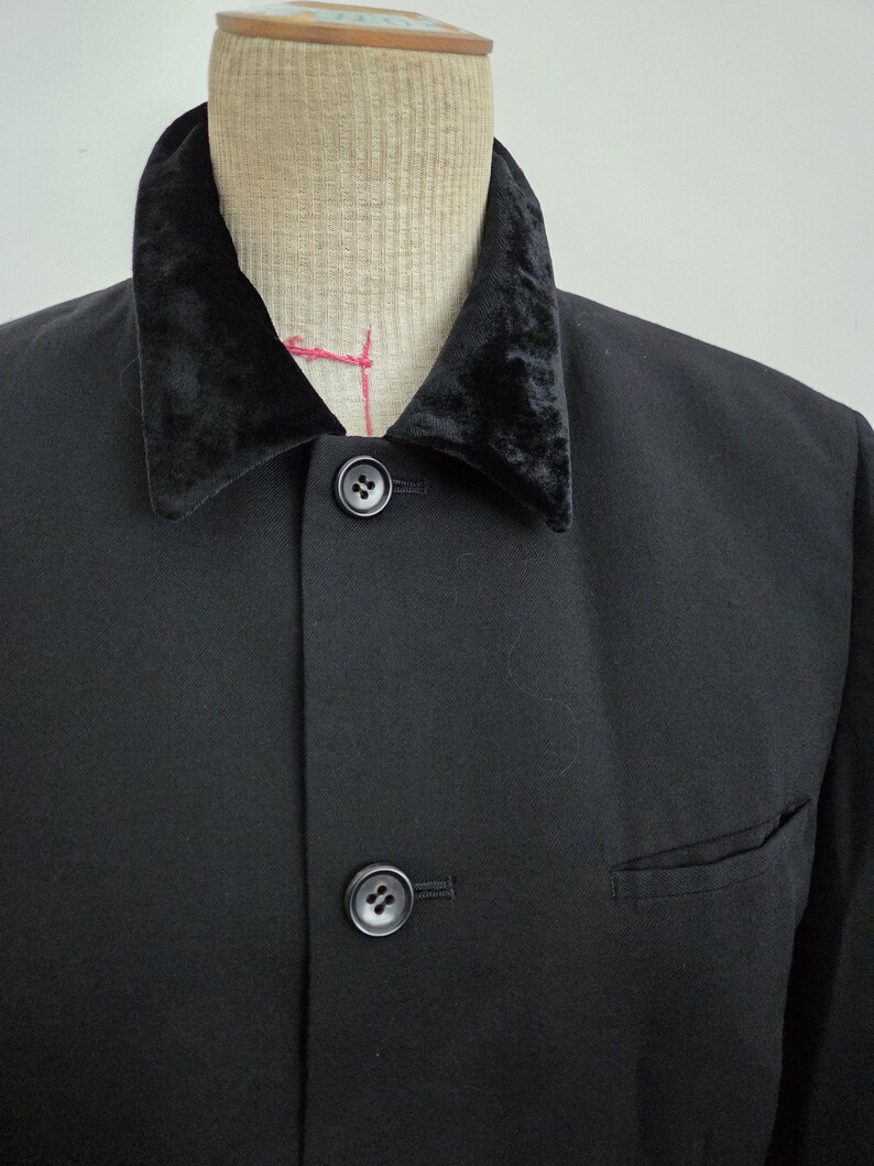 Puede incluir: Chaqueta negra con cuello de terciopelo y dos botones negros. La chaqueta tiene un bolsillo en el lado derecho. La chaqueta se exhibe en un maniqu&iacute;.