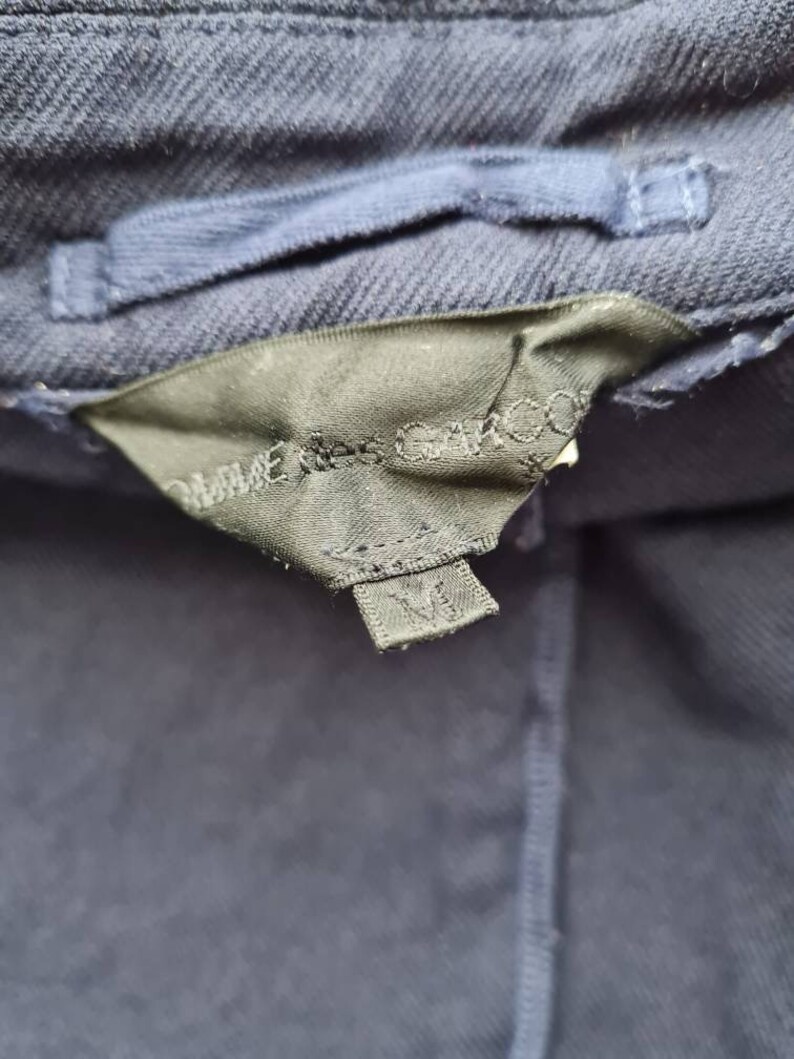 May include: A navy blue jacket with a black label that says "Made in China" and a size tag that says "M".