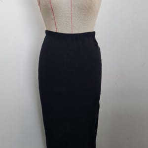 Pode incluir: Uma saia midi preta feita de um tecido macio e el&aacute;stico. A saia &eacute; de comprimento at&eacute; o joelho e tem um design simples e cl&aacute;ssico.