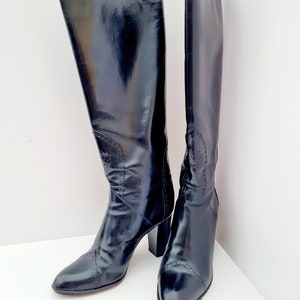 May include: A pair of black leather knee-high boots with a block heel and a pointed toe.