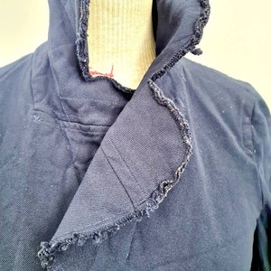 May include: A navy blue jacket with a frayed collar. The collar is folded over and the jacket is on a mannequin.