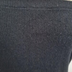 Pode incluir: Close-up de um tecido de malha canelada preta. O tecido &eacute; macio e tem uma textura sutil.