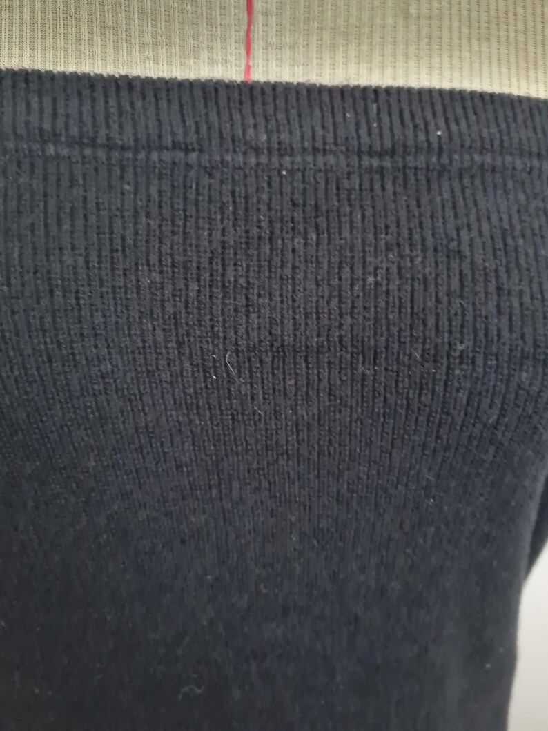 Pode incluir: Close-up de um tecido de malha canelada preta. O tecido &eacute; macio e tem uma textura sutil.