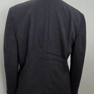 Puede incluir: Un blazer azul marino oscuro con cuello alto, visto desde atr&aacute;s. La chaqueta a medida tiene mangas largas y un dise&ntilde;o cl&aacute;sico. El blazer se exhibe en un maniqu&iacute;.