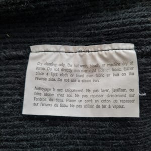 Pode incluir: Uma etiqueta de cuidados branca com texto preto que detalha as instru&ccedil;&otilde;es de limpeza a seco. O texto diz "Limpeza a seco apenas. N&atilde;o lavar, alvejar ou secar na m&aacute;quina em casa. N&atilde;o passar a ferro diretamente sobre o lado direito do tecido. Coloque um pano leve ou uma toalha sobre o tecido ou passe a ferro do avesso. N&atilde;o use um ferro a vapor. Nettoyage &agrave; sec uniquement. Ne pas laver, jav&eacute;liser, ou faire s&eacute;cher chez soi. Ne pas repasser directement sur l'endroit du tissu. Placer un carr&eacute; en coton ou repasser sur l'envers du tissu. Ne pas utiliser de fer &agrave; vapeur."