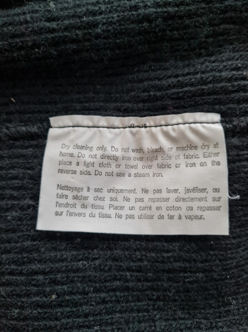 Pode incluir: Uma etiqueta de cuidados branca com texto preto que detalha as instru&ccedil;&otilde;es de limpeza a seco. O texto diz "Limpeza a seco apenas. N&atilde;o lavar, alvejar ou secar na m&aacute;quina em casa. N&atilde;o passar a ferro diretamente sobre o lado direito do tecido. Coloque um pano leve ou uma toalha sobre o tecido ou passe a ferro do avesso. N&atilde;o use um ferro a vapor. Nettoyage &agrave; sec uniquement. Ne pas laver, jav&eacute;liser, ou faire s&eacute;cher chez soi. Ne pas repasser directement sur l'endroit du tissu. Placer un carr&eacute; en coton ou repasser sur l'envers du tissu. Ne pas utiliser de fer &agrave; vapeur."