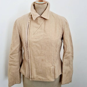 May include: A beige wool jacket with a zipper closure and a collar. The jacket has a fitted silhouette and a slightly flared hem.