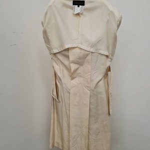 May include: A cream-coloured trench coat with a long, flowing silhouette. The coat has a belt and a collar. The label on the back of the coat reads "Gianfranco Ferre".