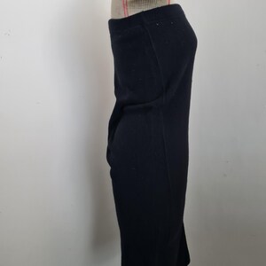 Pode incluir: Um vestido midi preto sem al&ccedil;as feito de tecido canelado. O vestido &eacute; ajustado e tem uma silhueta reta.