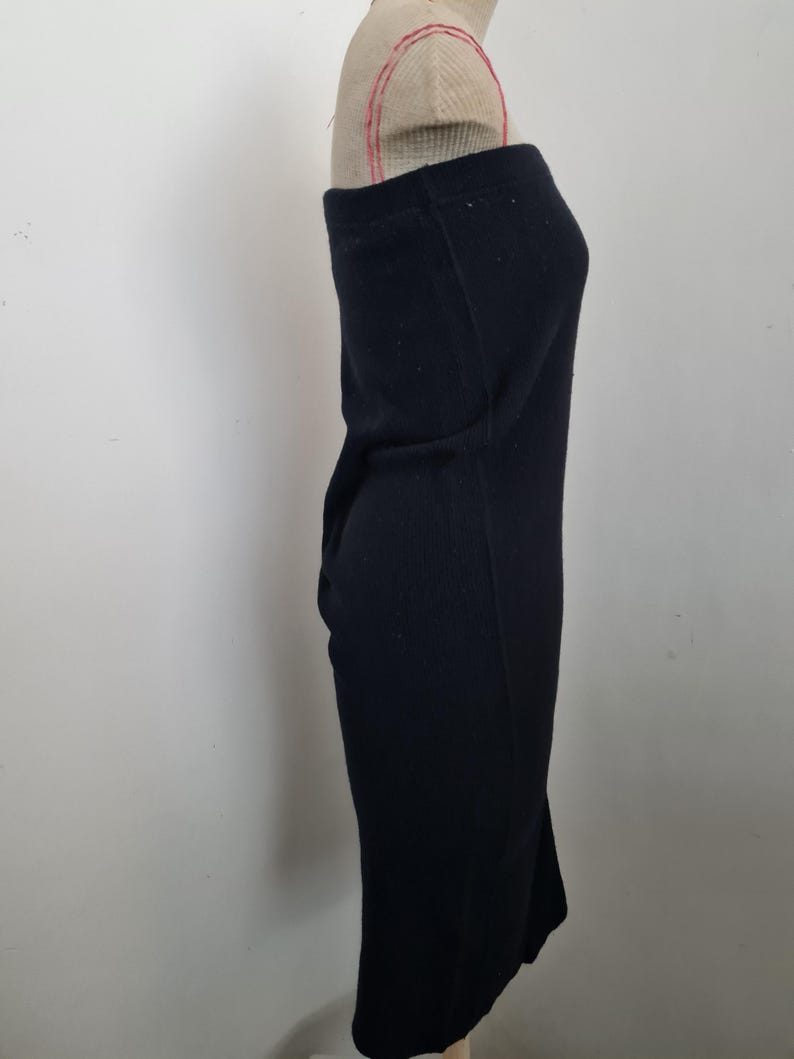 Pode incluir: Um vestido midi preto sem al&ccedil;as feito de tecido canelado. O vestido &eacute; ajustado e tem uma silhueta reta.