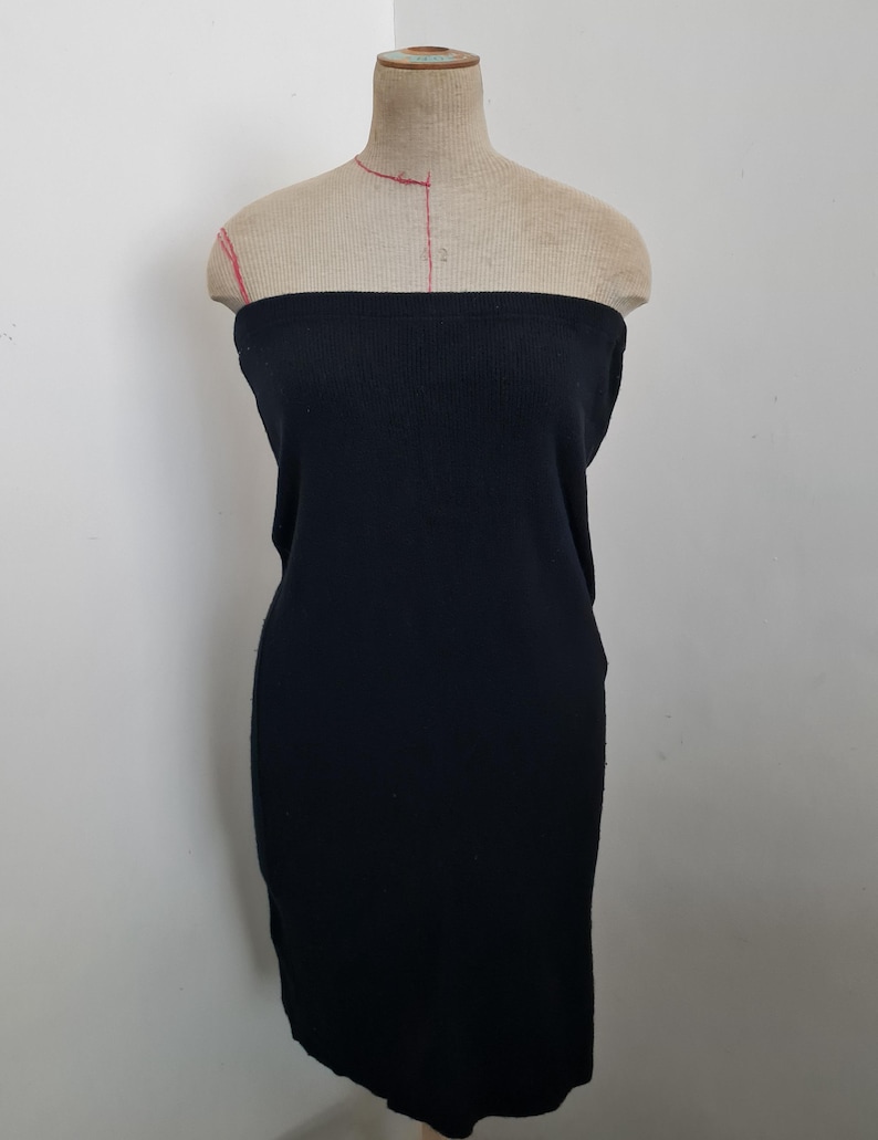 Pode incluir: Um vestido preto sem al&ccedil;as feito de tecido de malha canelada. O vestido &eacute; justo e tem uma saia reta.