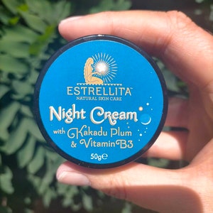 May include: A blue jar with a black lid and a gold label that reads "Estrellita Natural Skin Care Night Cream with Kakadu Plum & Vitamin B3 50g e".