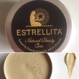 Könnte beinhalten: Eine silberne Dose mit einem schwarzen Etikett, auf dem "Estrellita Natural Beauty Care" und "Getestet von Freunden und Familie, nicht an Tieren" steht. Das Etikett zeigt auch ein stilisiertes Bild einer Frau mit langen Haaren.