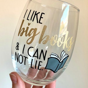 May include: A clear glass wine glass with a gold and black vinyl decal that reads "I like big books & I can not lie."  A blue and white illustration of an open book is next to the text.