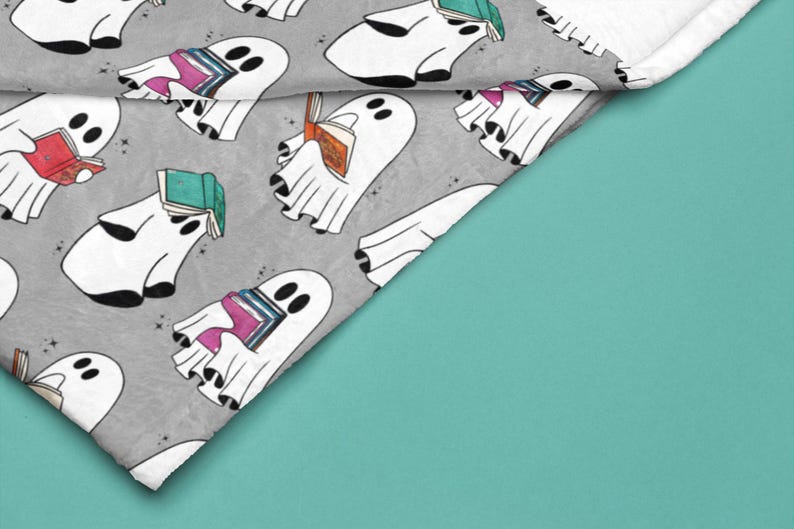May include: A gray and white fabric with a repeating pattern of white ghosts holding stacks of colorful books. The ghosts are outlined in black and have small black eyes. The fabric has a subtle sparkle.