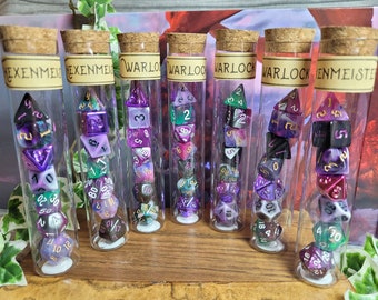 May include: Seven glass tubes with cork tops contain sets of purple, green, and black dice with gold and silver accents. The tubes are labeled with the words "EXENMEIS", "WARLO", and "ENMEISTE".