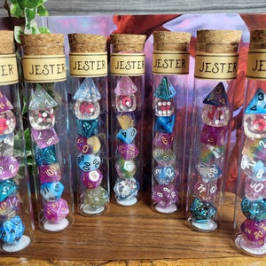 May include: Seven glass tubes filled with colourful dice. Each tube has a label that reads "Jester".