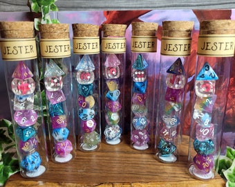 Può includere: Sette tubi di vetro pieni di dadi colorati. Ogni tubo ha un'etichetta che recita "Jester".