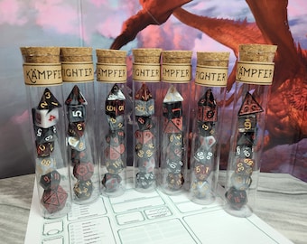Puede incluir: Seis tubos de vidrio transparente con tapas de corcho, cada uno contiene un juego de dados negros, blancos y rojos con detalles dorados. Los tubos están etiquetados con la palabra "KÄMPFEIGHTER" o "AMPFER".