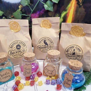 Könnte beinhalten: Eine Auswahl an Fantasy-Artikeln, darunter Papiertüten mit goldenen Wachssiegeln, Gläser mit Korken und farbige Würfel. Die Tüten sind mit Aufschriften wie "Moonlit Cove Brewing Co." und "The Raven's Blend Moonbrew Co." versehen.