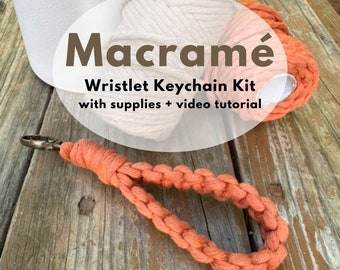 May include: Macrame Wristlet Keychain Kit with supplies + video tutorial. A close-up of a completed orange macrame wristlet keychain with a metal clasp.