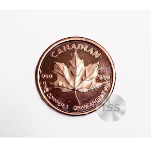 Może przedstawiać: Kanadyjska złota moneta z liściem klonu, znakiem czystości 999 i wagą 1 gram.