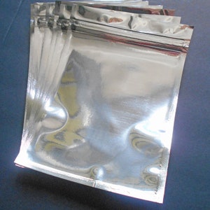 May include: A stack of silver foil zippered pouches, ideal for packaging small items.
