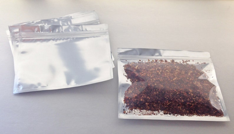 May include: Two silver zippered pouches, one empty and one filled with red and brown dried chili flakes.