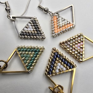 May include: Five triangular earrings featuring woven seed beads in various color patterns, including black, white, peach, green, blue, and metallic gold. Each earring is set within a geometric metal frame and includes a silver or gold hook wire.