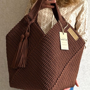 May include: A brown crocheted tote bag with a brown tassel. The bag has a tag that says "Lunar Cat".