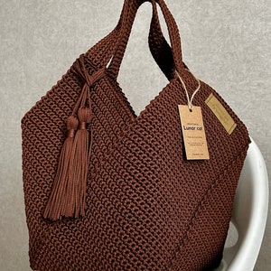 May include: A brown crocheted tote bag with a long brown tassel. The bag has a brown paper tag that says "Lunar cat".