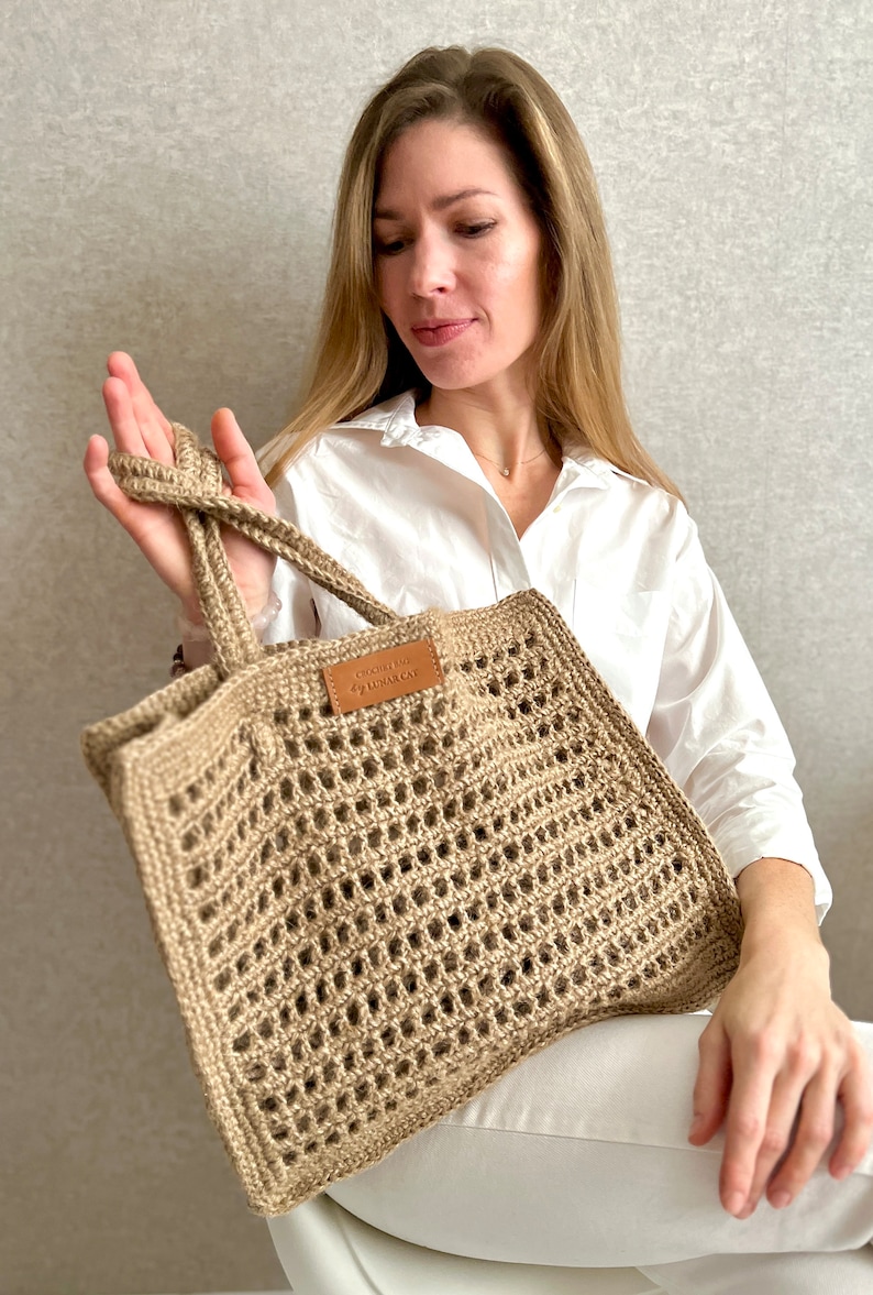 May include: A beige crocheted tote bag with a leather label that says "Crochet by Alejandra".